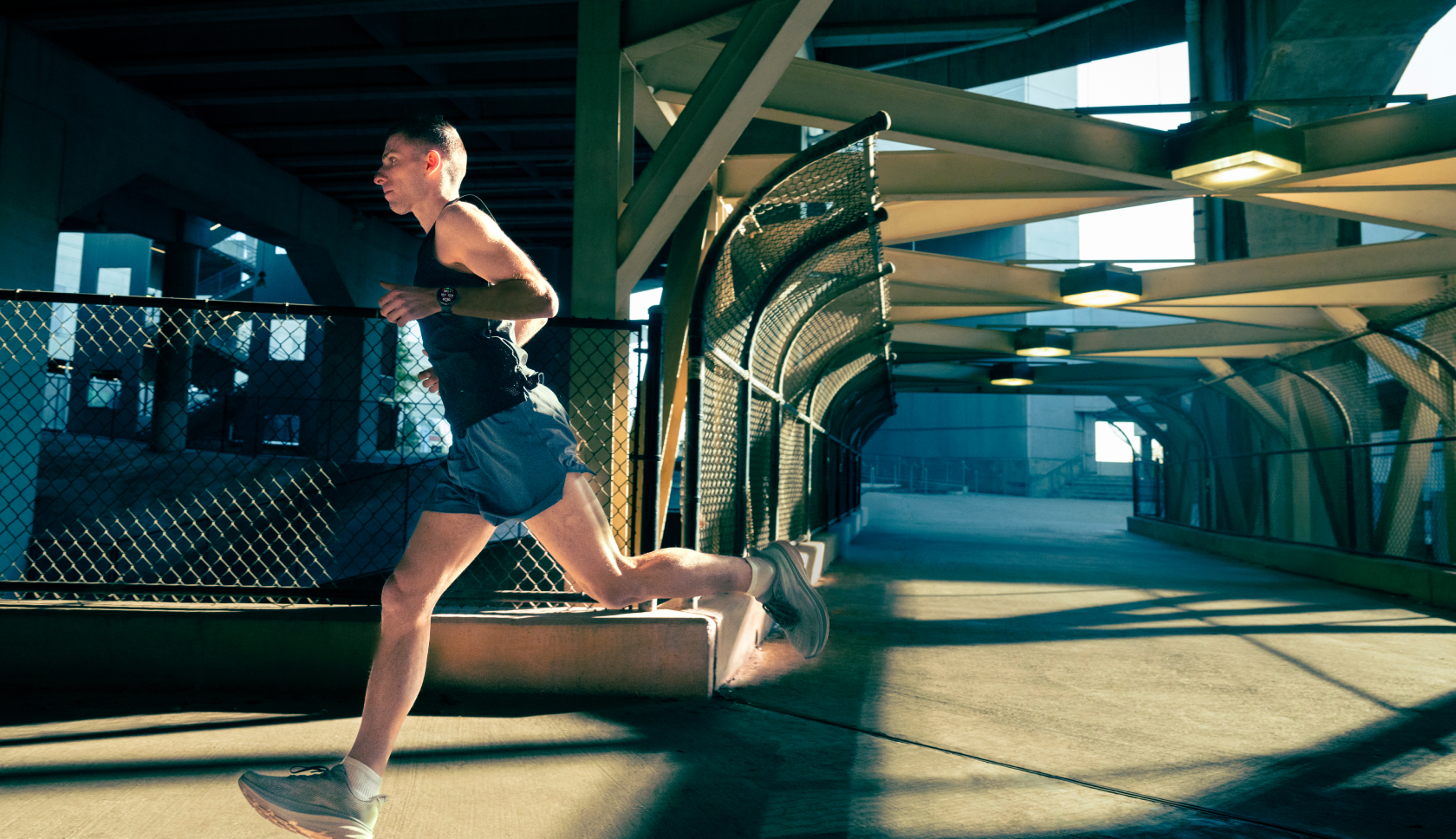 Een man rent over een betonnen brug.